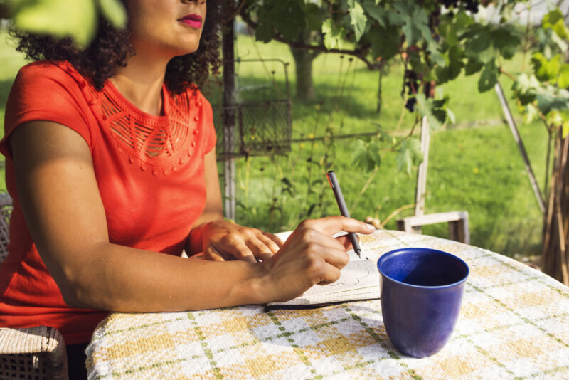 Woman at a table outside taking notes