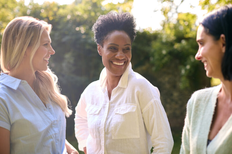 Three Smiling Mature Female Friends Outdoors Spending Time In Countryside Together