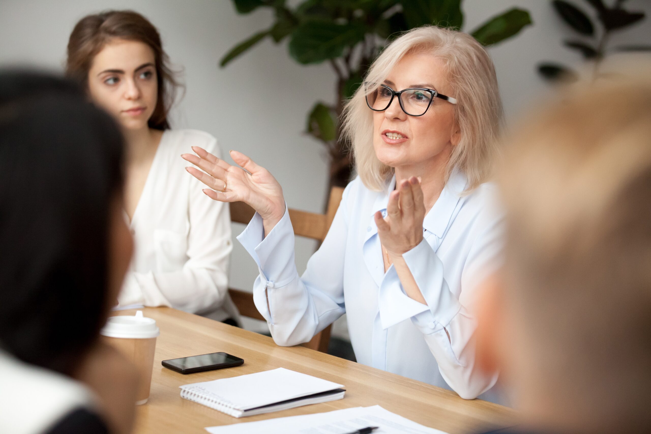 Middle aged businesswoman, teacher or business coach speaking to young people