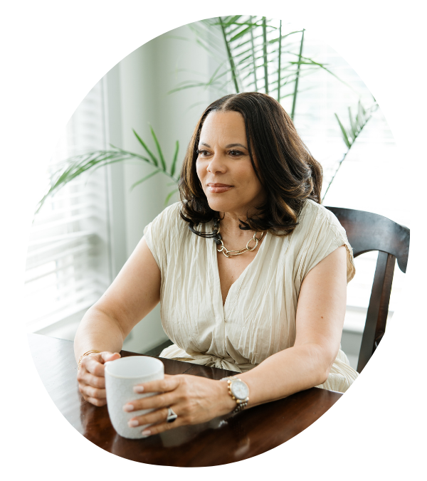 Woman sitting at a table with a mug and a plant in the background